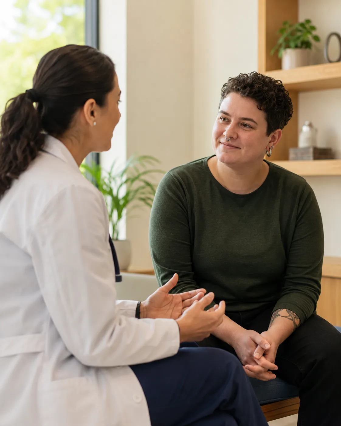 A clinician in a white coat talking with a patient in a bright consultation room