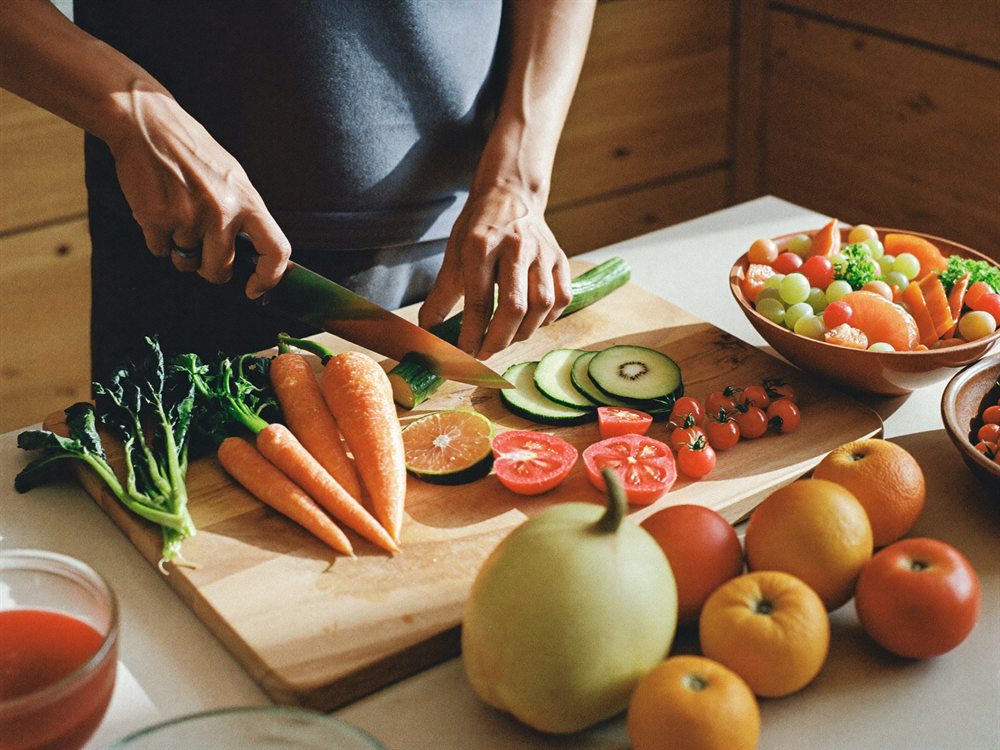 Fresh vegetables and fruit being chopped for a healthy meal